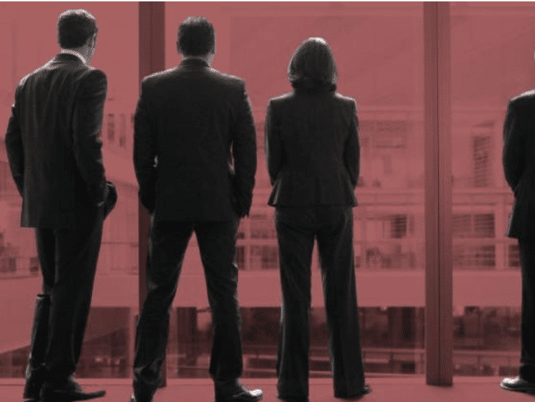 Three people standing in suits presenting as the company board